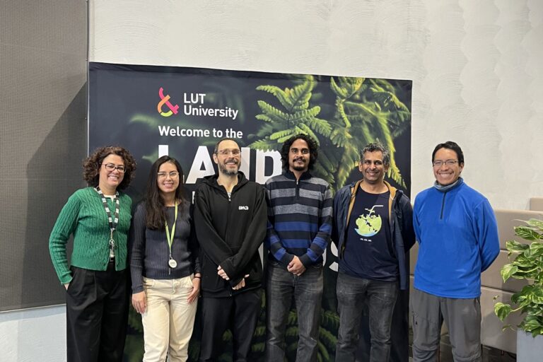 Group of people in front of an LUT University banner smiling.