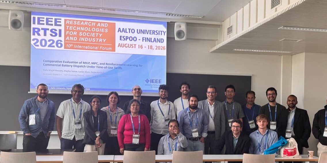 Coalesce partners posing for photo in front of presentation at the IEEE RTSI Conference 2026 in Finland