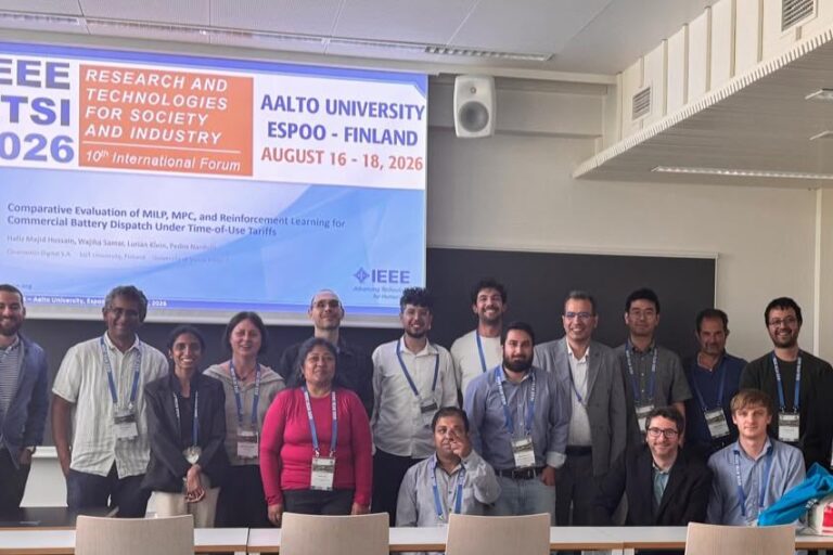 Coalesce partners posing for photo in front of presentation at the IEEE RTSI Conference 2026 in Finland