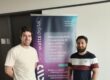 Majid with colleague posing in front of Cleanwatts Digital sign.