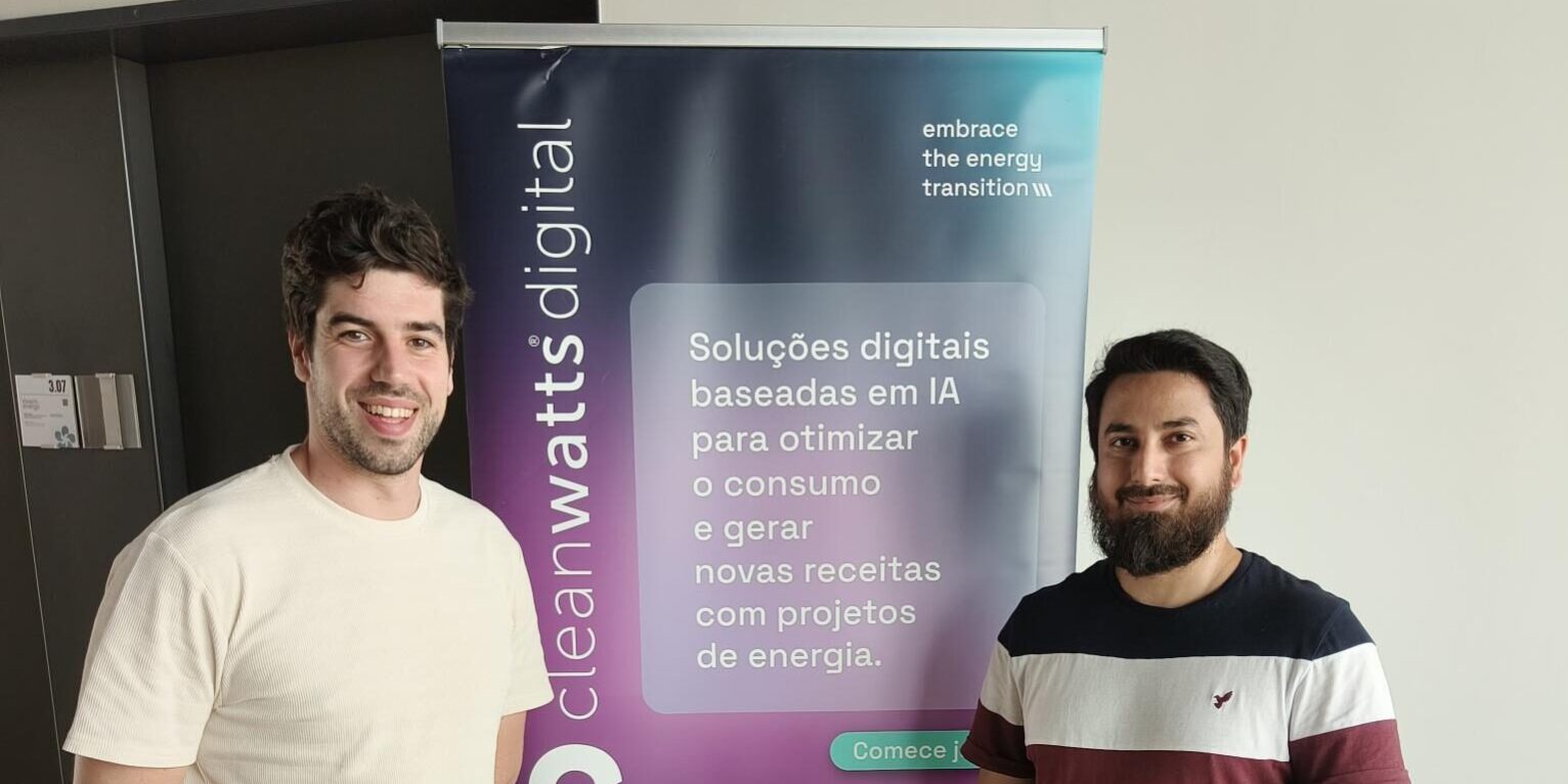Majid with colleague posing in front of Cleanwatts Digital sign.